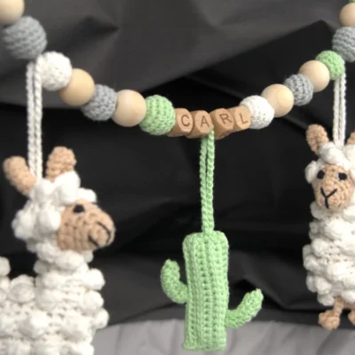 Personalized stroller chain with llama motif and the name Carl attached to a stroller.