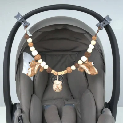 Personalisierte Kinderwagenkette mit Eichhörnchen-Motiv und Namen Janis an der Babyschale befestigt.