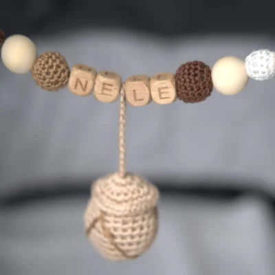 Close‑up: personalized stroller chain with deer/nut motif and the name Nele