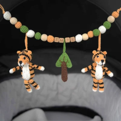 Personalisierte Kinderwagenkette mit Tiger-Motiv und Namen Emil am Kinderwagen befestigt.